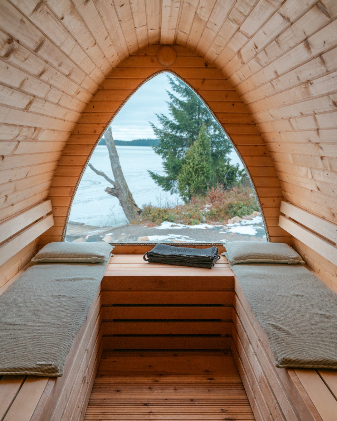 Zwei grüne Saunsofa Sets liegen in einer Holzsauna.